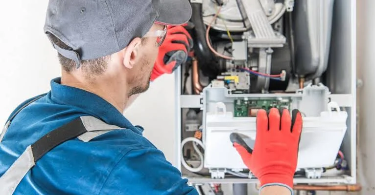 Technician troubleshooting components inside a residential heating system